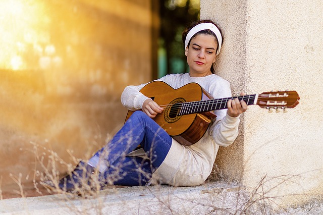 Girl Playing Guitar. Photo by Gavin Whitner. License: CC BY 2.0.